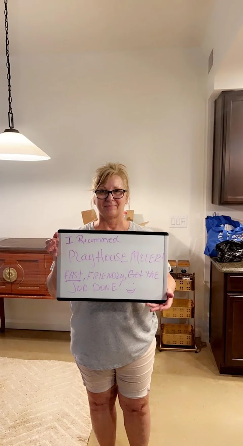 Customer holding a board recommending Playhouse Moving as fast, friendly and able to get the job done